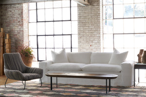  White sofa in a showroom with a multicolored rug. A striped chair in black is on the left. Photographed in Otis White. 