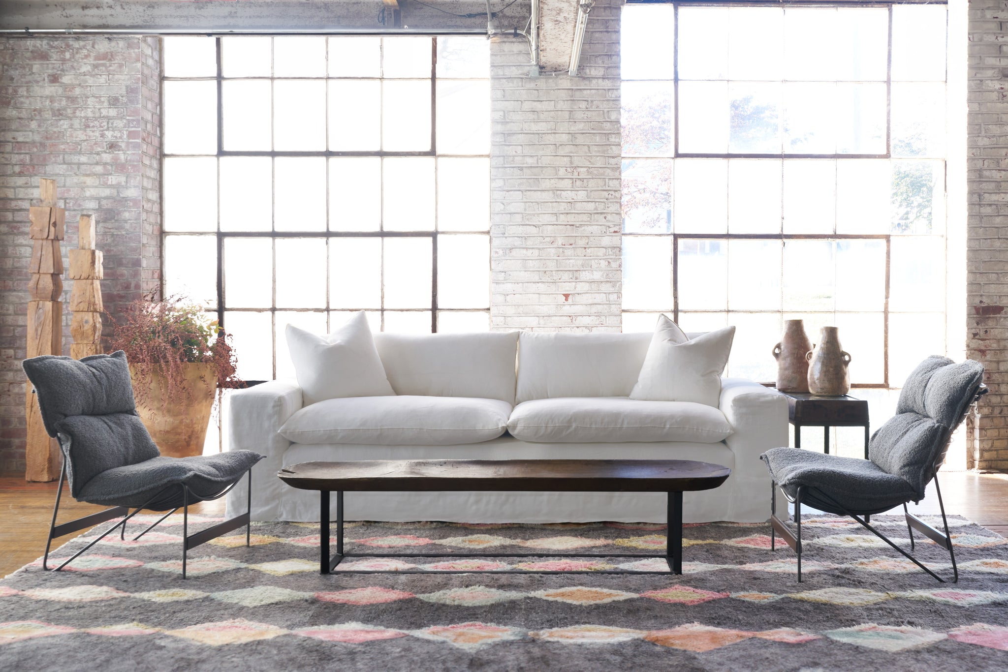  White sofa in a showroom with a multicolored rug with a chair on each side . Photographed in Otis White. 