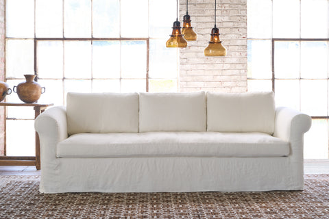 White sofa in a showroom with 3 glass light pendants. Photographed in Brevard Ivory.