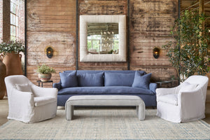  Blue sofa in front of a wood wall with 2 white chairs and a grey leather bench. Photographed in Brevard Slate. 