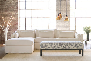  White slipcovered sectional with a bench with white and black blowers and wood base. Photographed in Pisa Nero. 