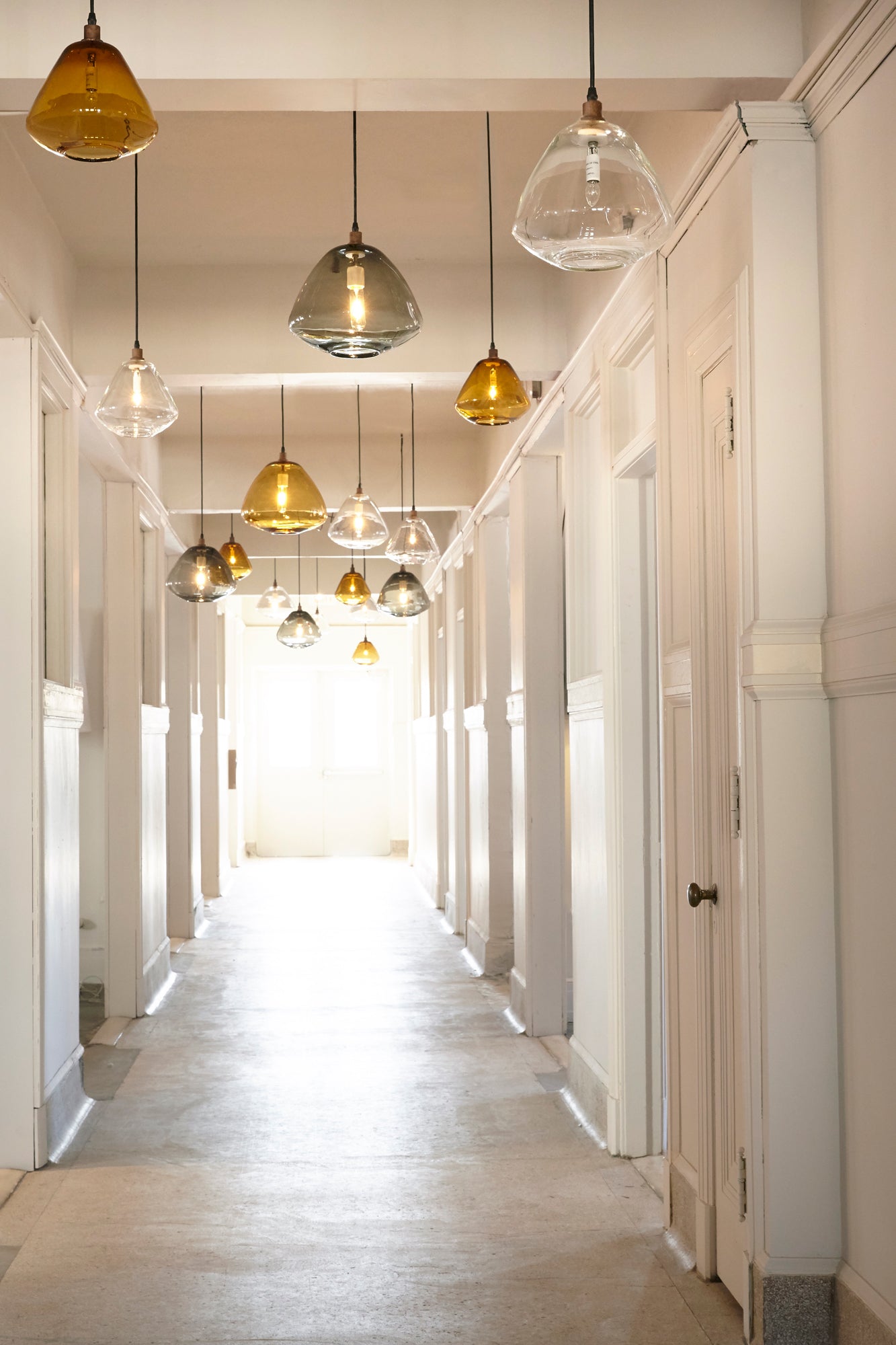  Long hallway with glass pendants hanging from ceiling. Colors-Auburn, Smoke & Clear 