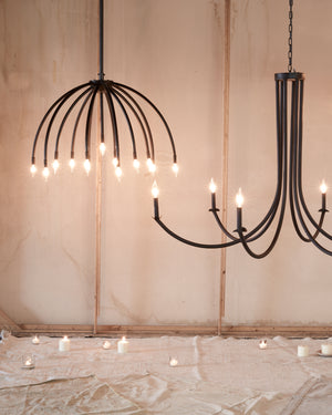  Two chandeliers hanging from ceiling. Curved arms on chandelier and black finish.  