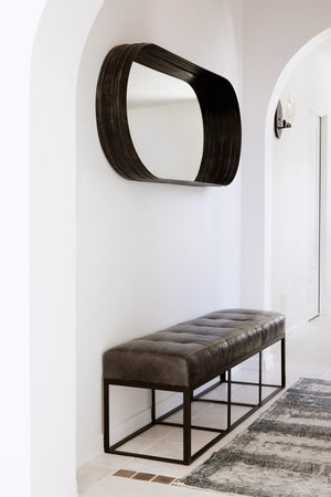  Cruz bench in Indiana Charcoal that sits in a white hallway. Above the bench hangs a mirror. Photographed in Indiana Charcoal. 