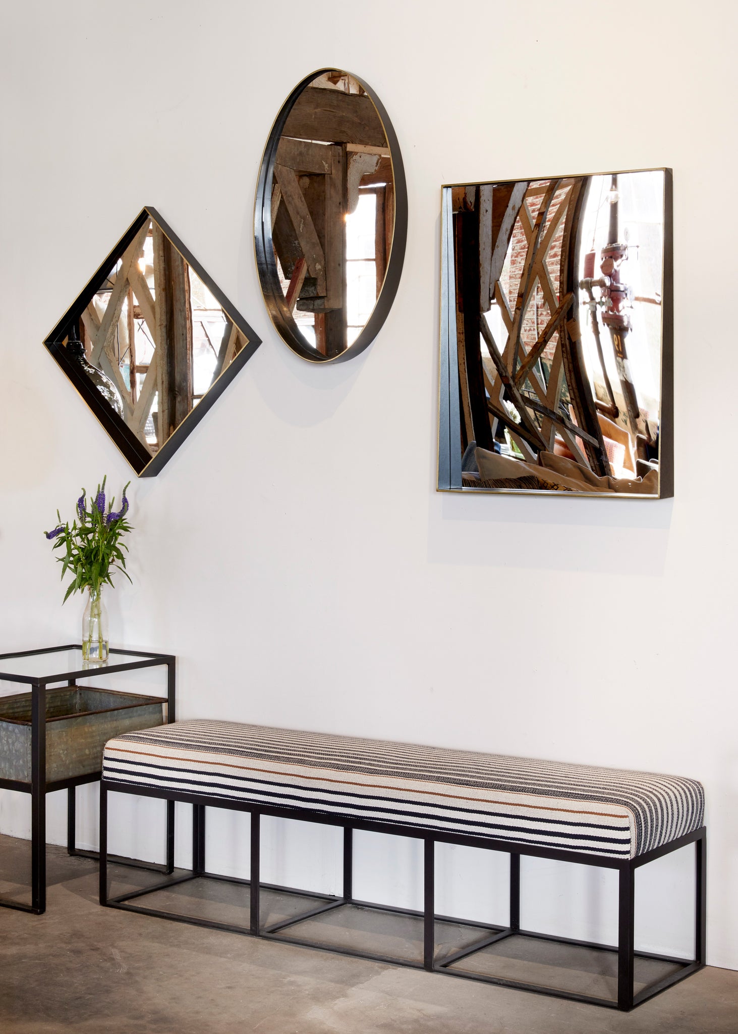  Cruz bench in Rayas Fino next to white wall with three mirrors hanging above it. Photographed in Rayas Fino. 