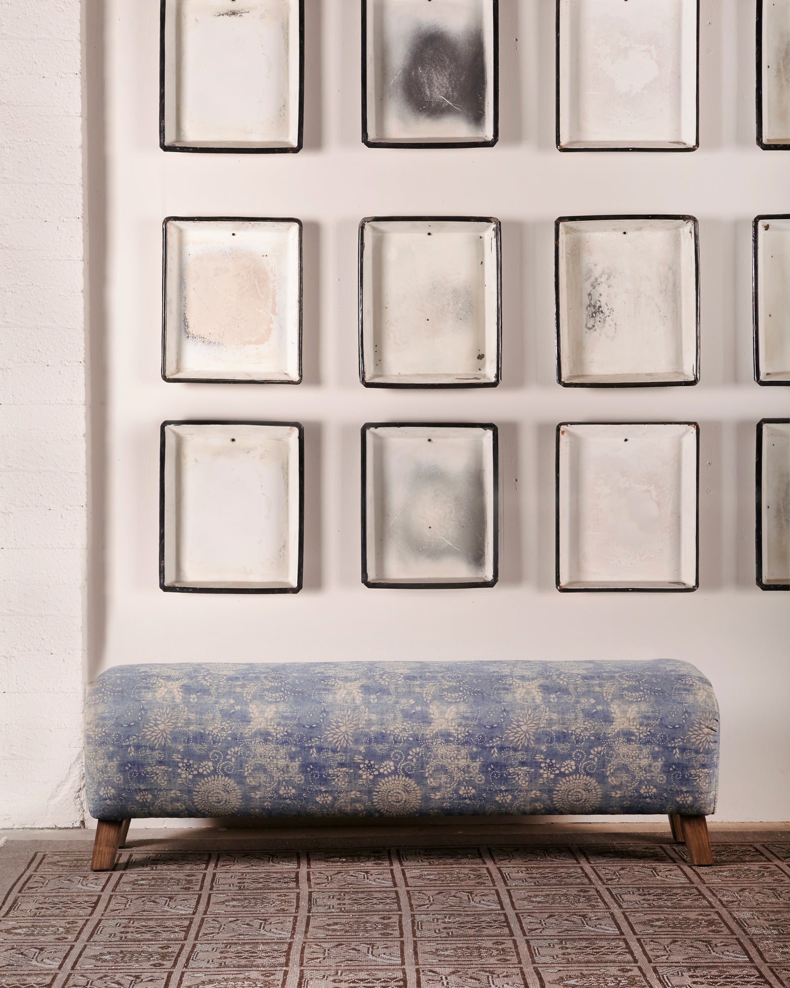  Mason bench in Mariko Indigo. In the background are multiple frames that hangs on a white wall. Photographed in Mariko Indigo 