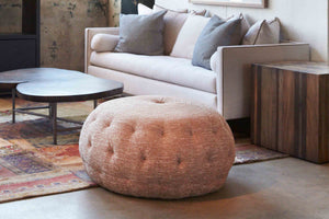  Pouf Ottoman 36 in Aster Clay (discontinued) next to a side table and sofa. Photographed in Aster Clay. 