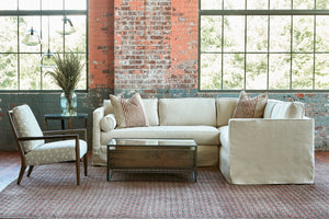  Cream colored sectional in an industrial showroom with a chair with flowers on the left and a wood and glass coffee table in front. Photographed in Vanocur Natural. 