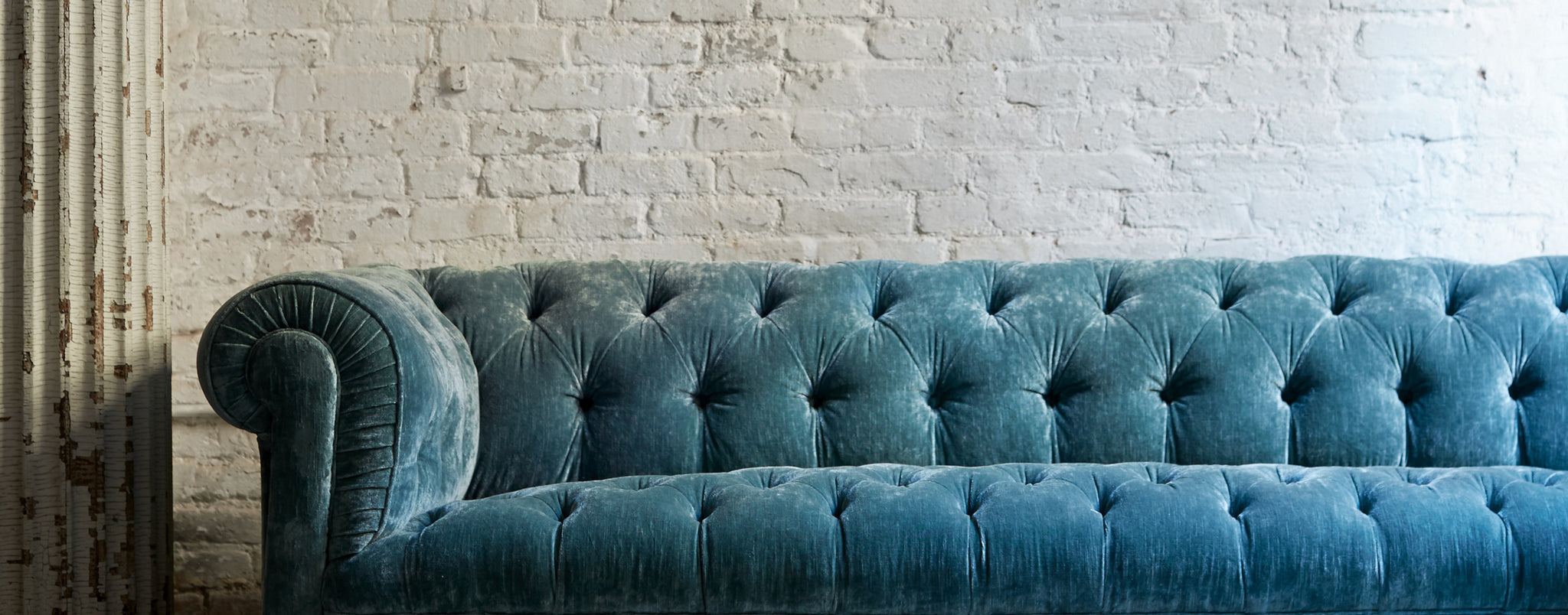 blue sofa in front of white brick wall