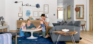 family in a living room with grey sofa white coffee table and art work on the walls