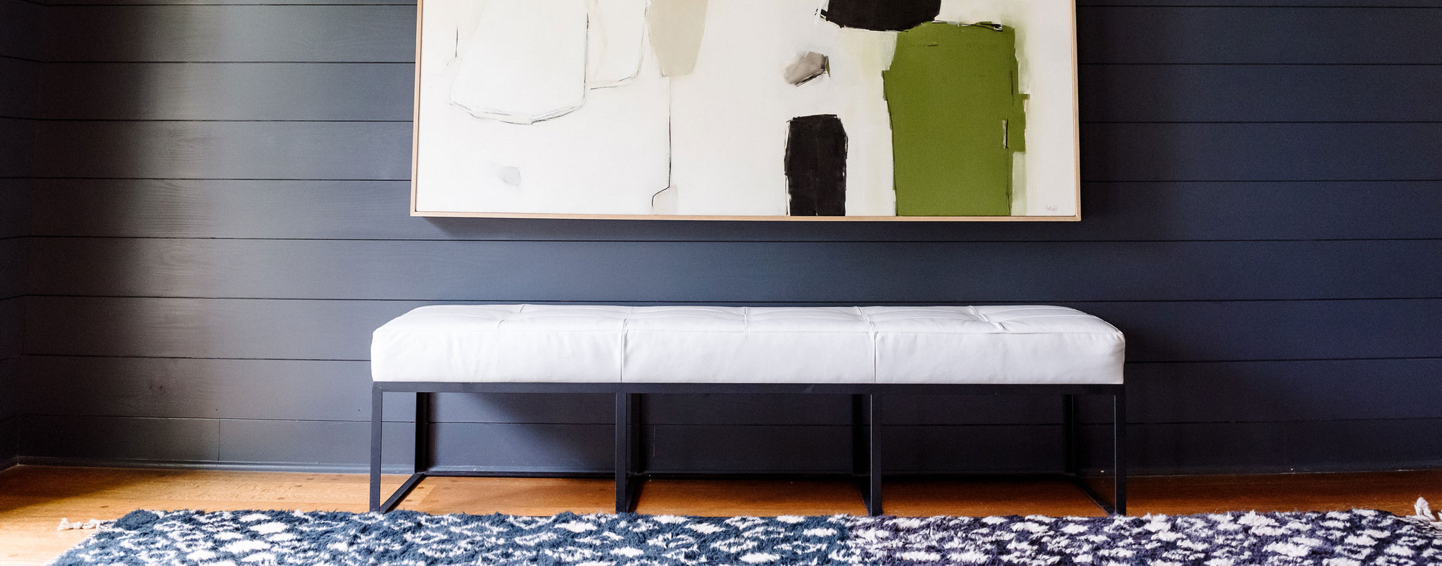 black wooden wall with a metal base bench in the center and a painting above