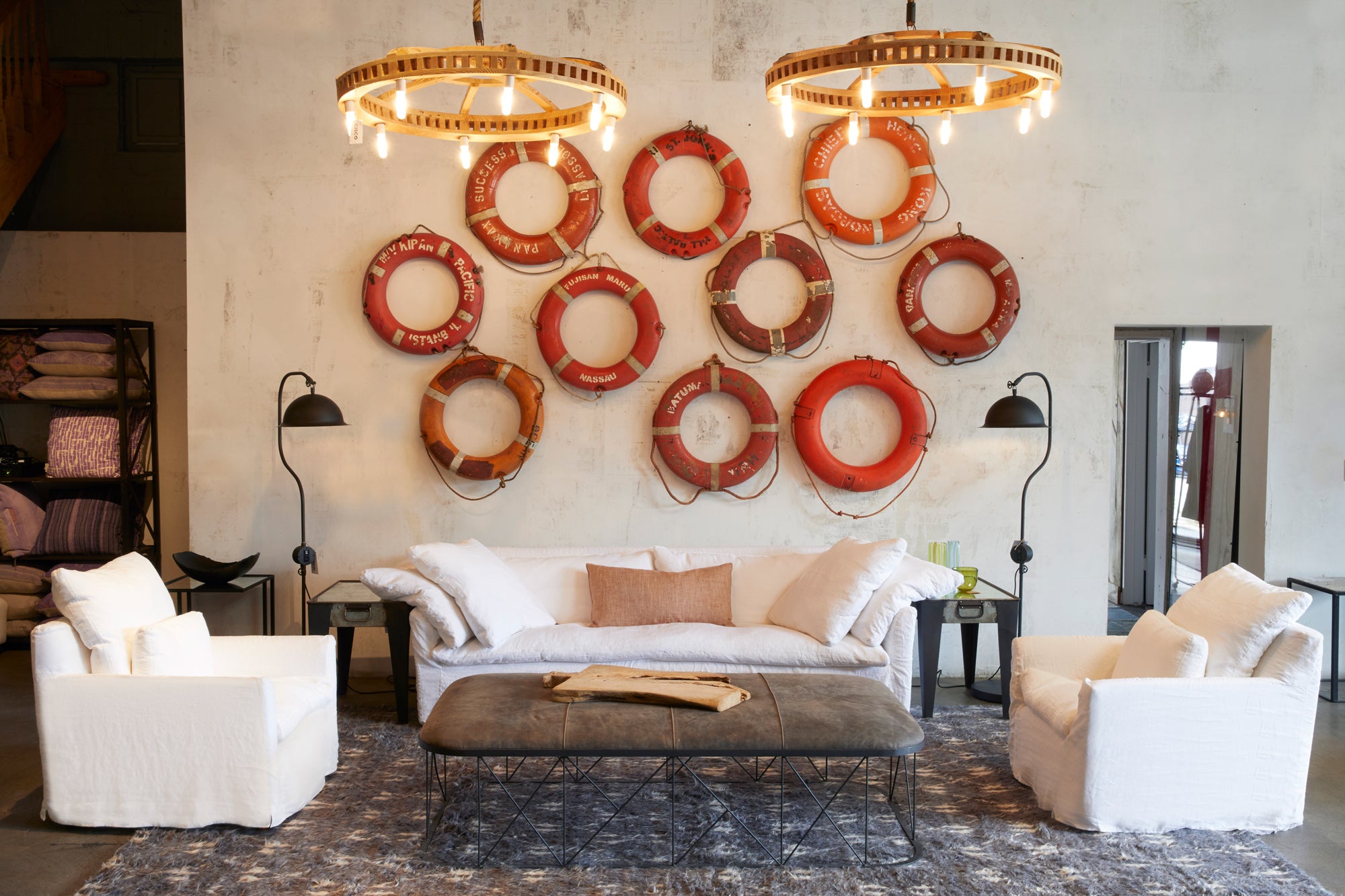  interior shot of Cisco Home store with white sofa and matching white chairs and wall of life preservers mounted as art on the wall 