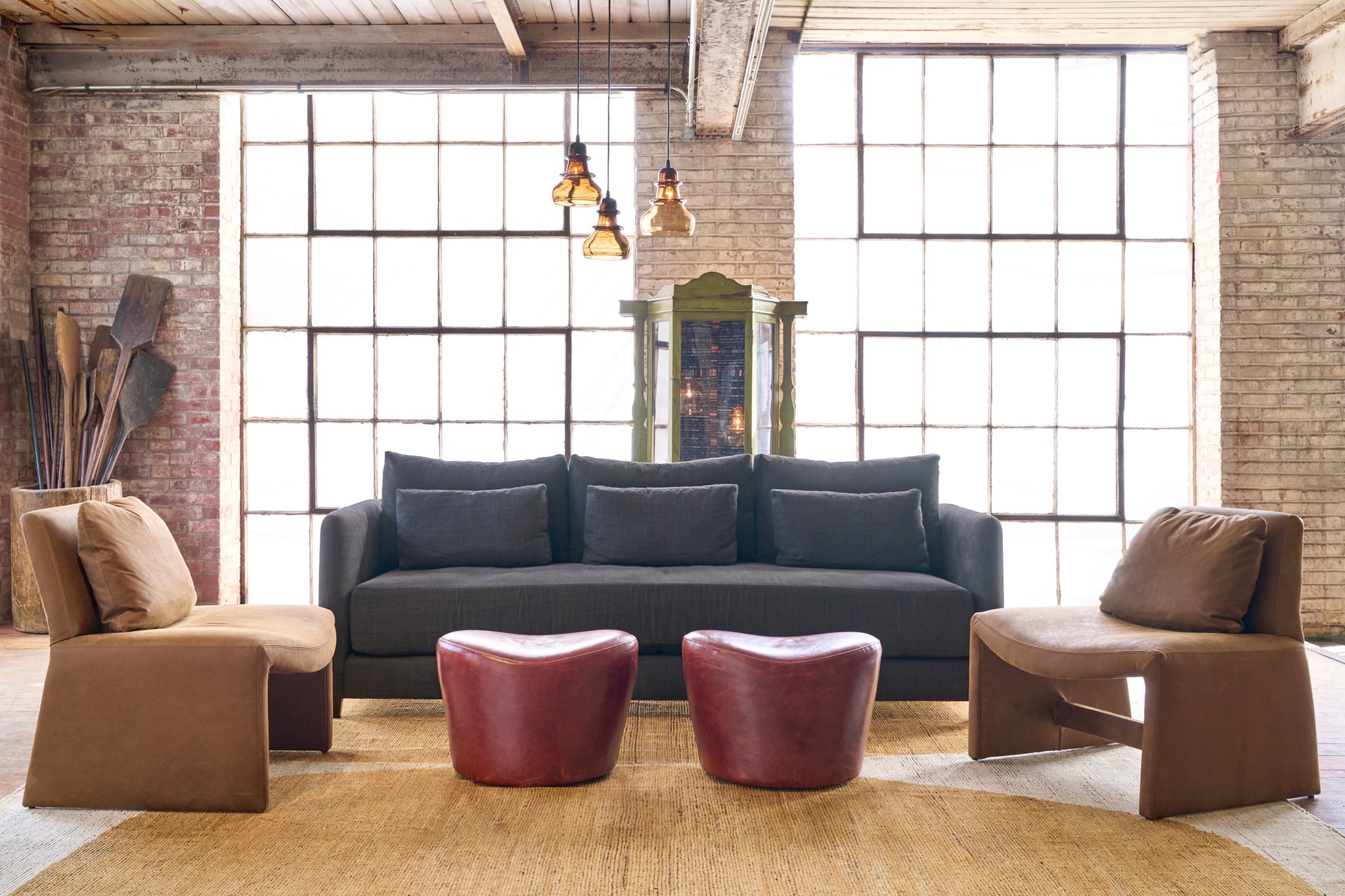  Black sofa on a yellow rug with brown leather chairs on each side. Two red leather ottomans in the middle. Photographed in Solvang Chianti. 