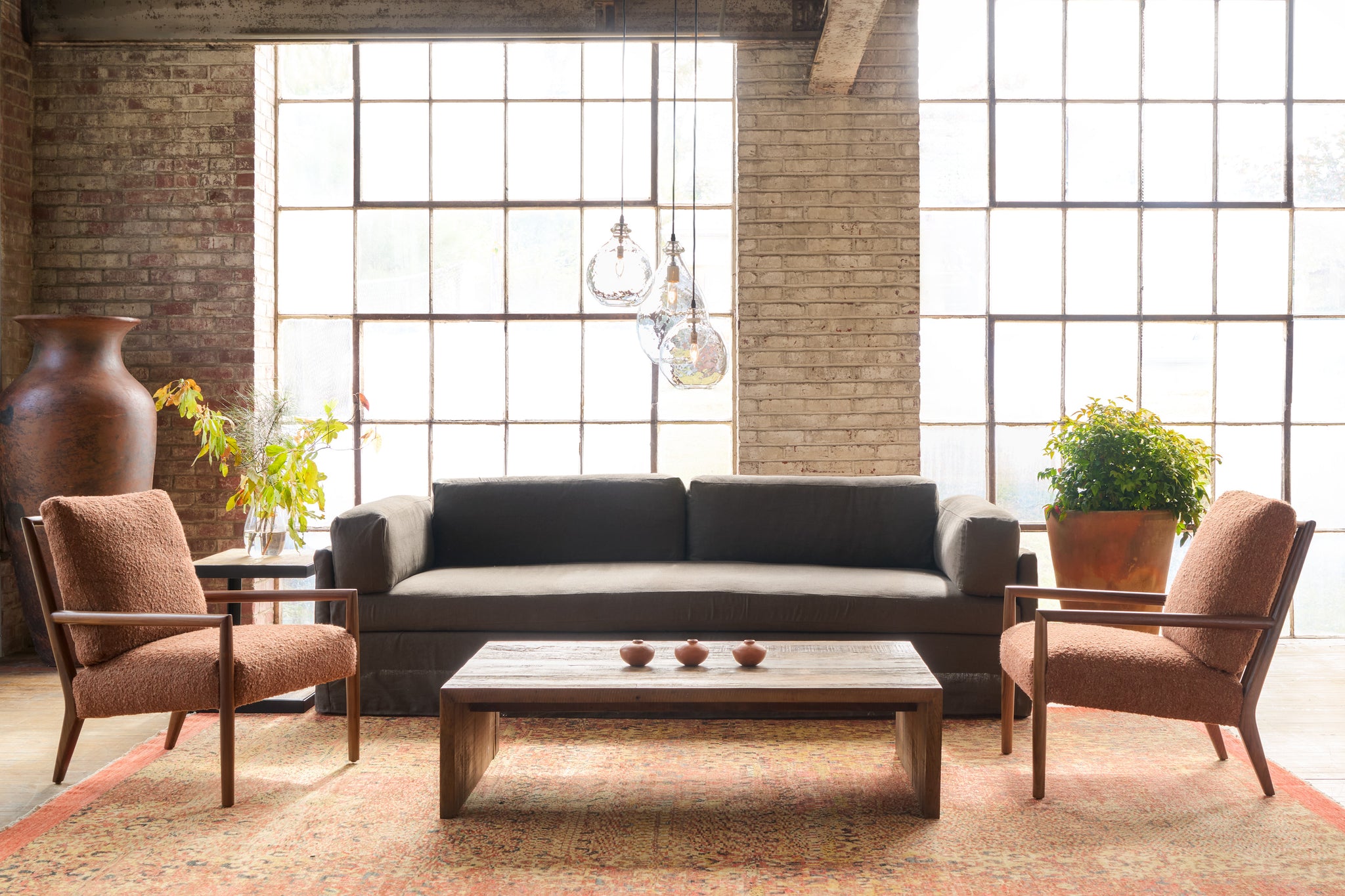  Modern living room with a brown sofa, two rust armchairs, and a wooden coffee table. Photographed in Miles Walnut. 