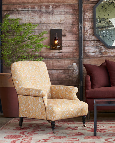Patterned armchair in a room with wooden walls, a mirror, and a plant. Photographed in Flora Saffron.