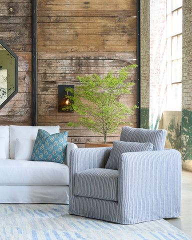 Living room with a striped armchair, white sofa, and wooden wall. Photographed in Hickory Blue.