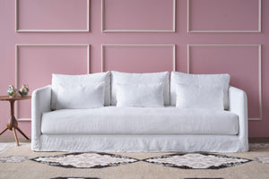  White sofa in front of a pink wall with a rug underneath. Photographed in Otis White. 