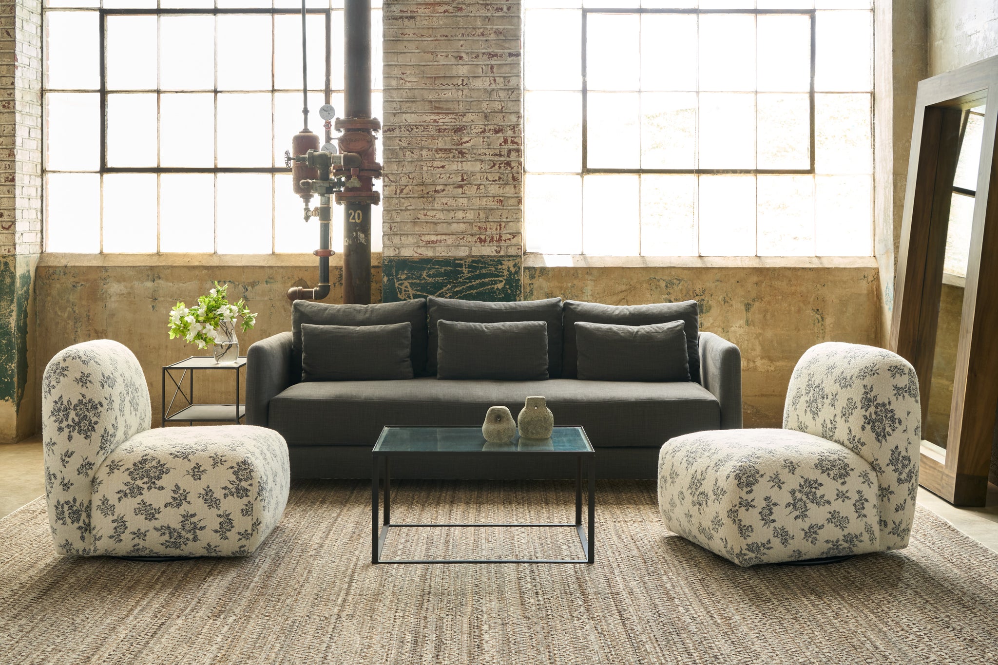  Black sofa with 2 round shaped chairs in black and white floral fabric in front of large windows. Photographed in Piso Nero. 