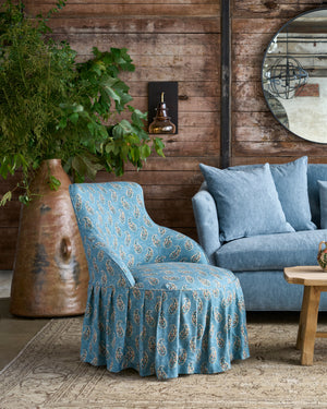  Chair with skirt next to a blue sofa. Photographed in Gigi Teal. 