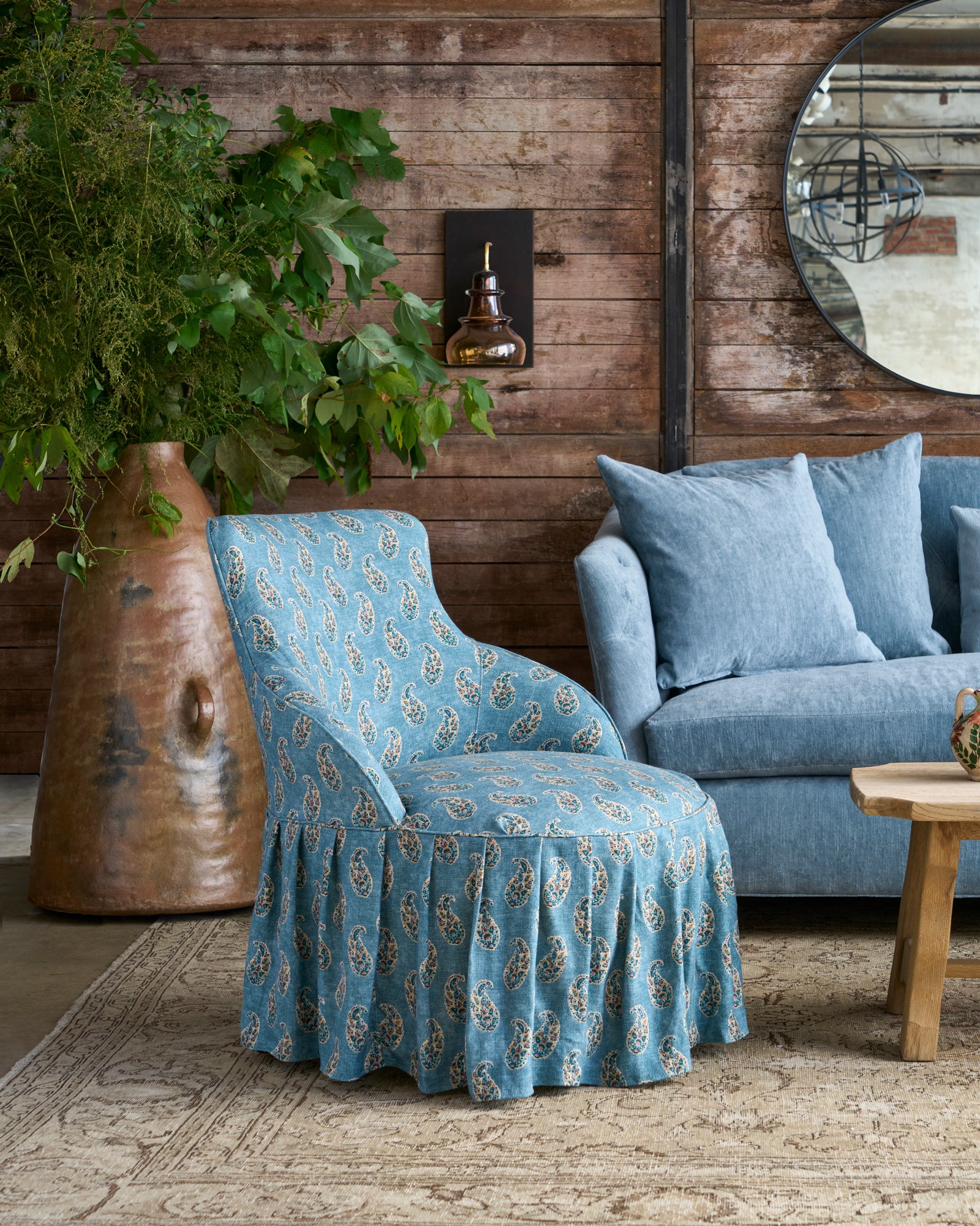  Chair with skirt next to a blue sofa. Photographed in Gigi Teal. 