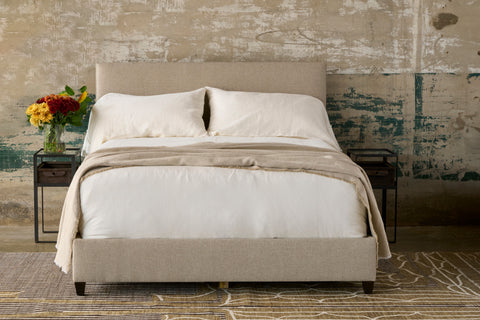 Beige bed on a cement wa