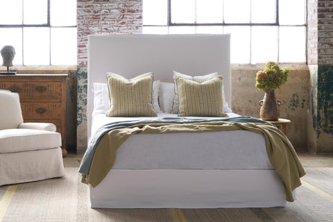 Bed in a showroom with a chair on the left. Photographed in Luna White.