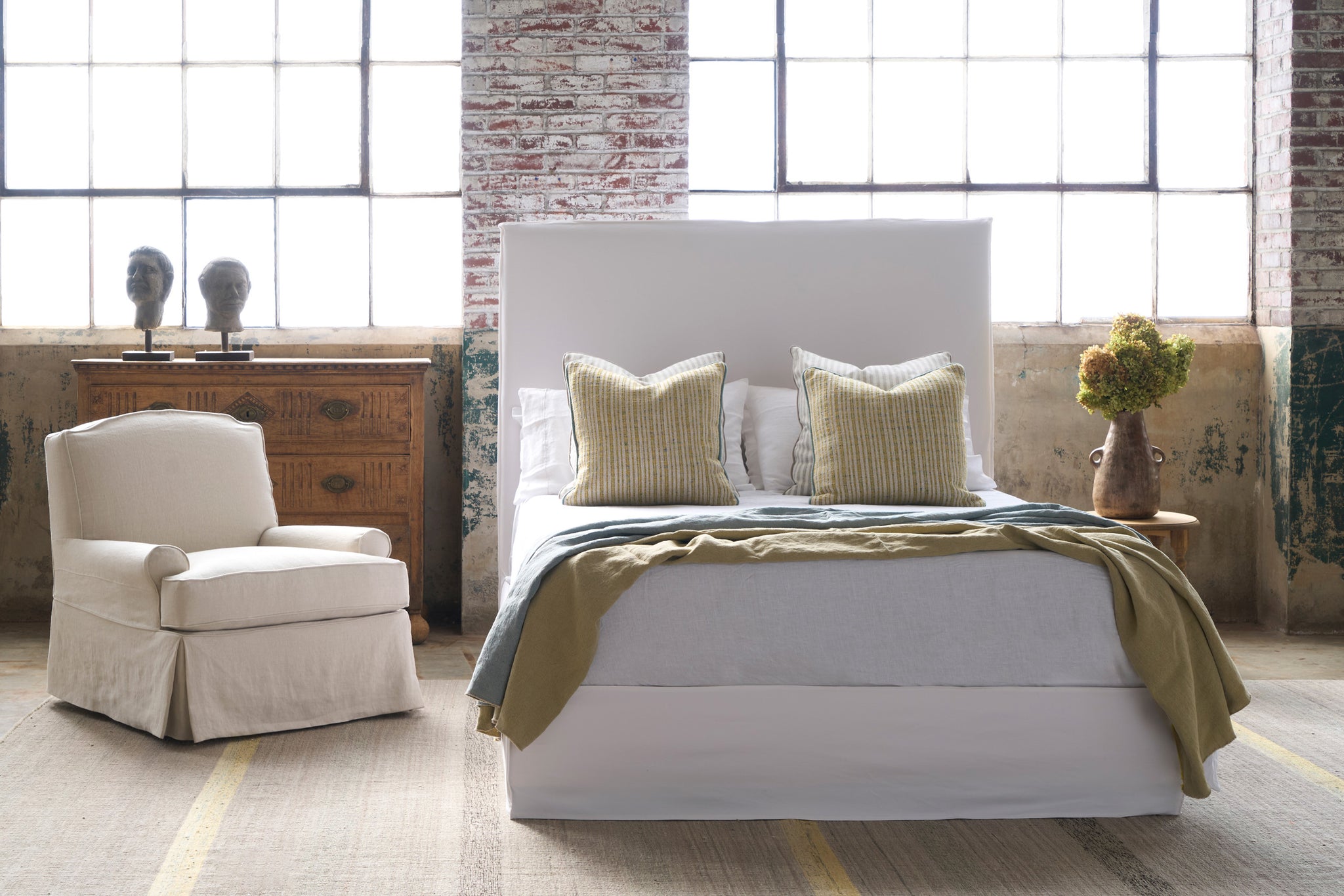  Bed in a showroom with a chair on the left. Photographed in Luna White. 