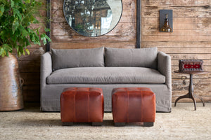  Two leather ottomans in leather in front of a brown sofa. Photographed in JD Rye Warm Grey. 