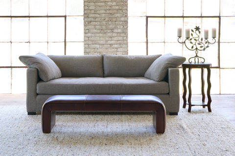 Grey sofa in front of windows with a brown leather bench. Photographed in Sandy Smoke.