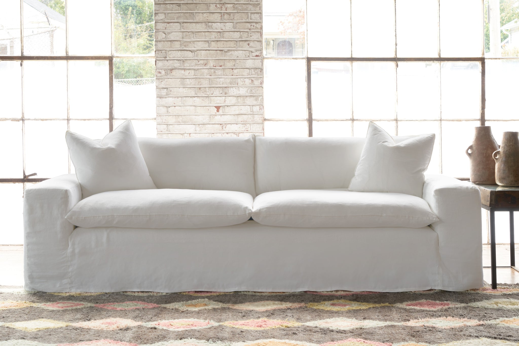  White sofa in a showroom with a multicolored rug. Photographed in Otis White. 