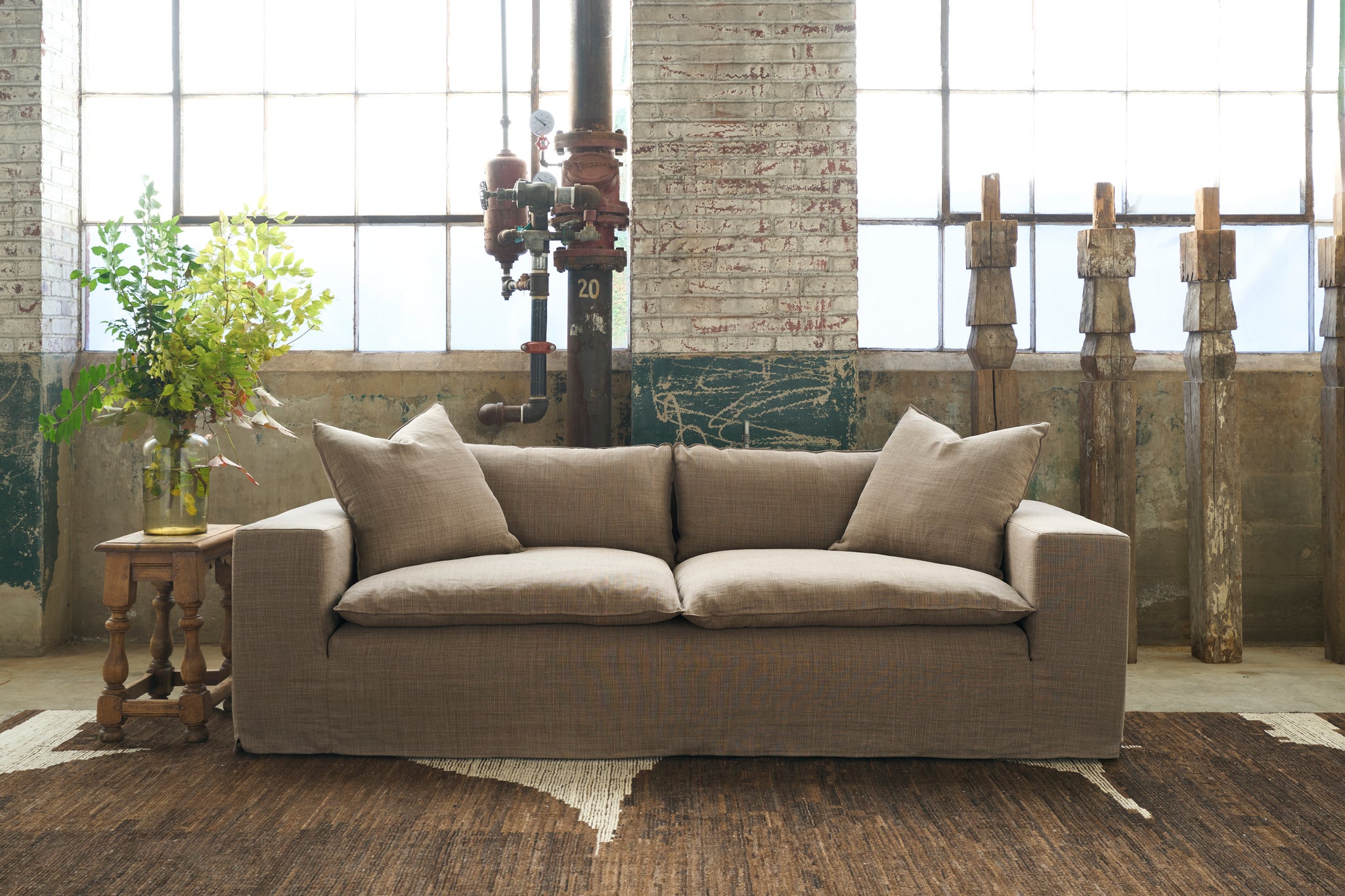  Brown Sofa in a showroom with a brown rug in front of large windows. Photographed in Rye Acorn. 