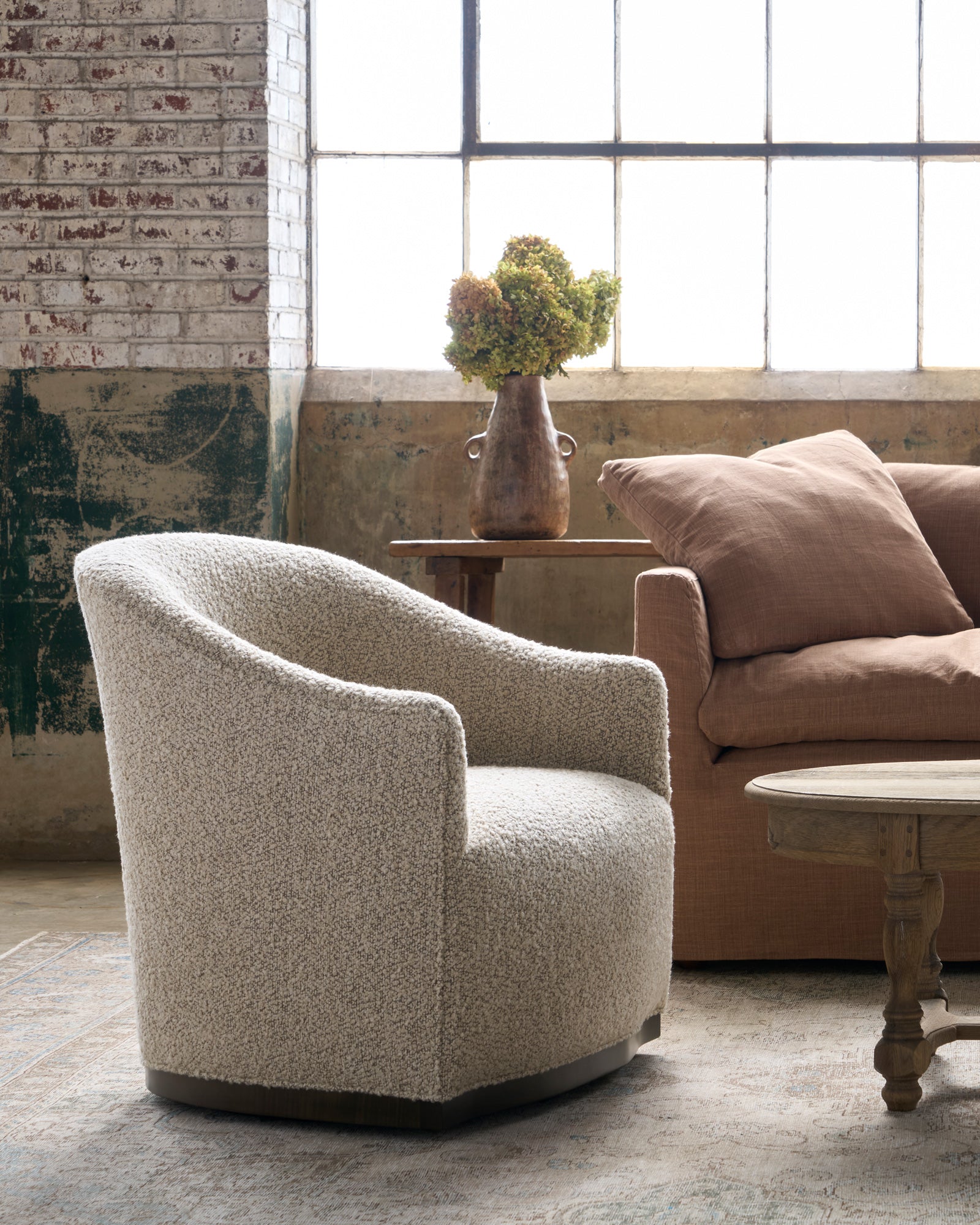  Chair with a wood base next to a brown sofa. Photographed in Knobby Mineral. 