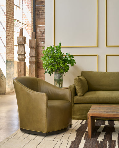 Green armchair and sofa in a stylish room with a plant and wooden table. Photographed in Gustavo Olive.