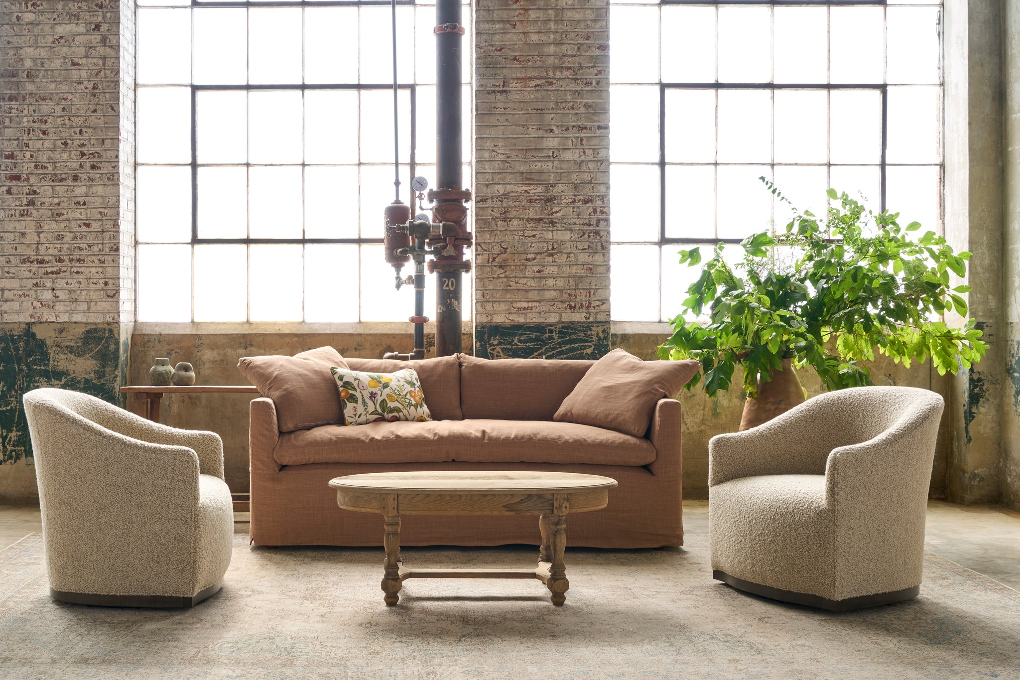  Chairs with a wood base next to a brown sofa. Large pot with green foliage on the right. Oval wood coffee table in front. Photographed in Knobby Mineral. 