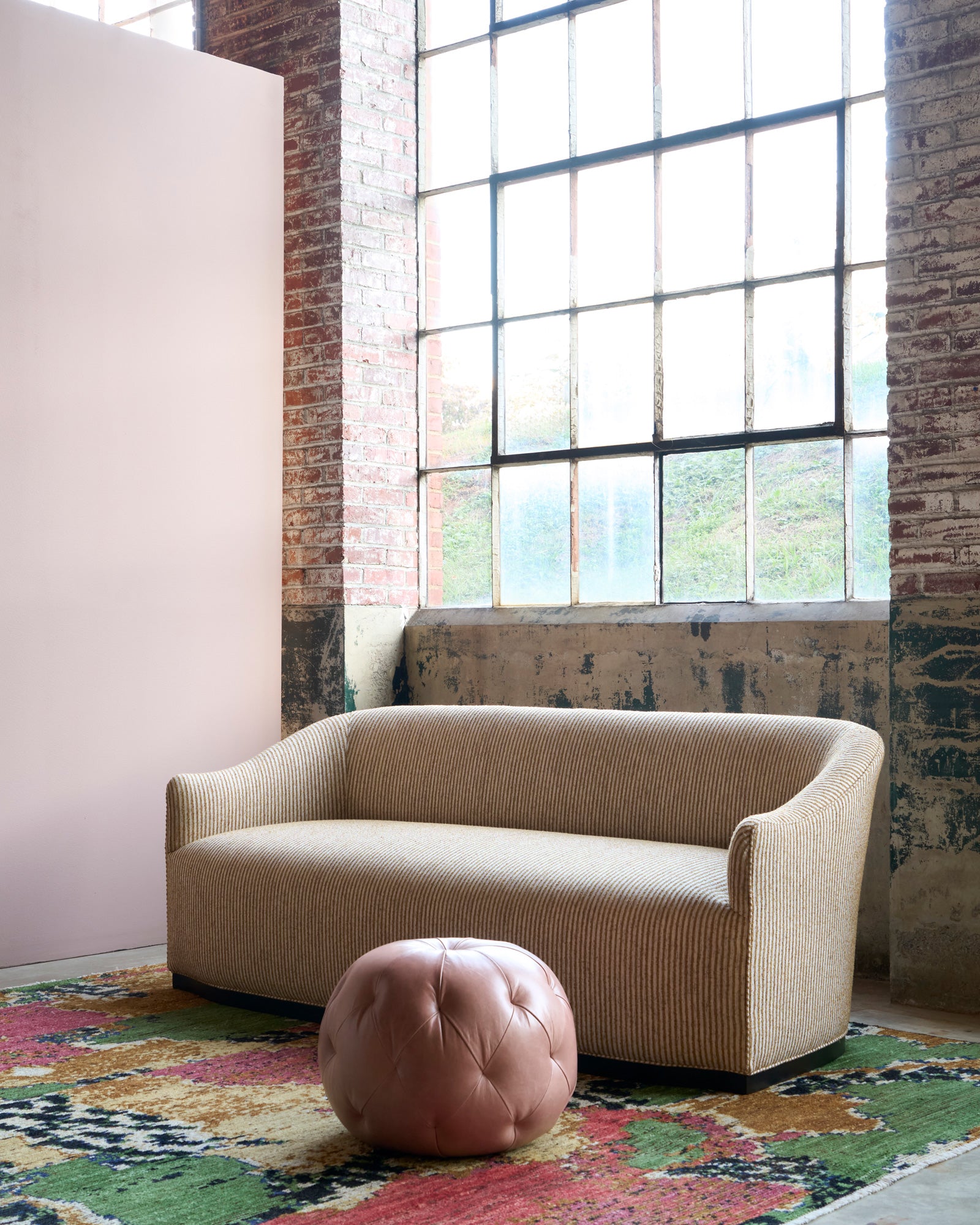  Beige sofa in a room with large windows and a colorful rug. Photographed in Shiloh Tumeric. 