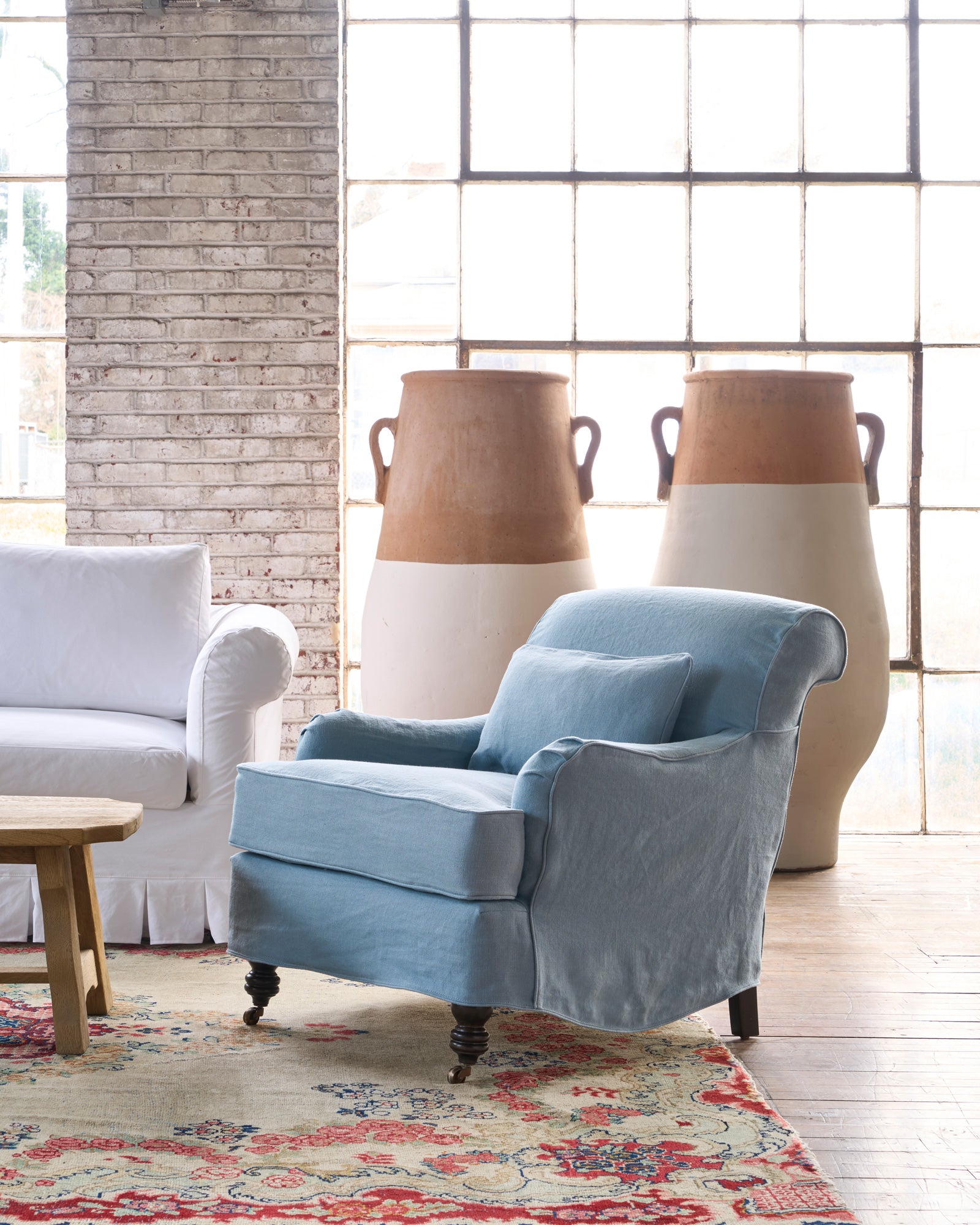  Blue slipcovered chair in front of 2 painted terracotta pots. Photographed in Brevard Ciel. 