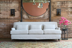  Sofa in front of a wood wall with pink flowers on a table on the right. Photographed in Brevard Mist. 