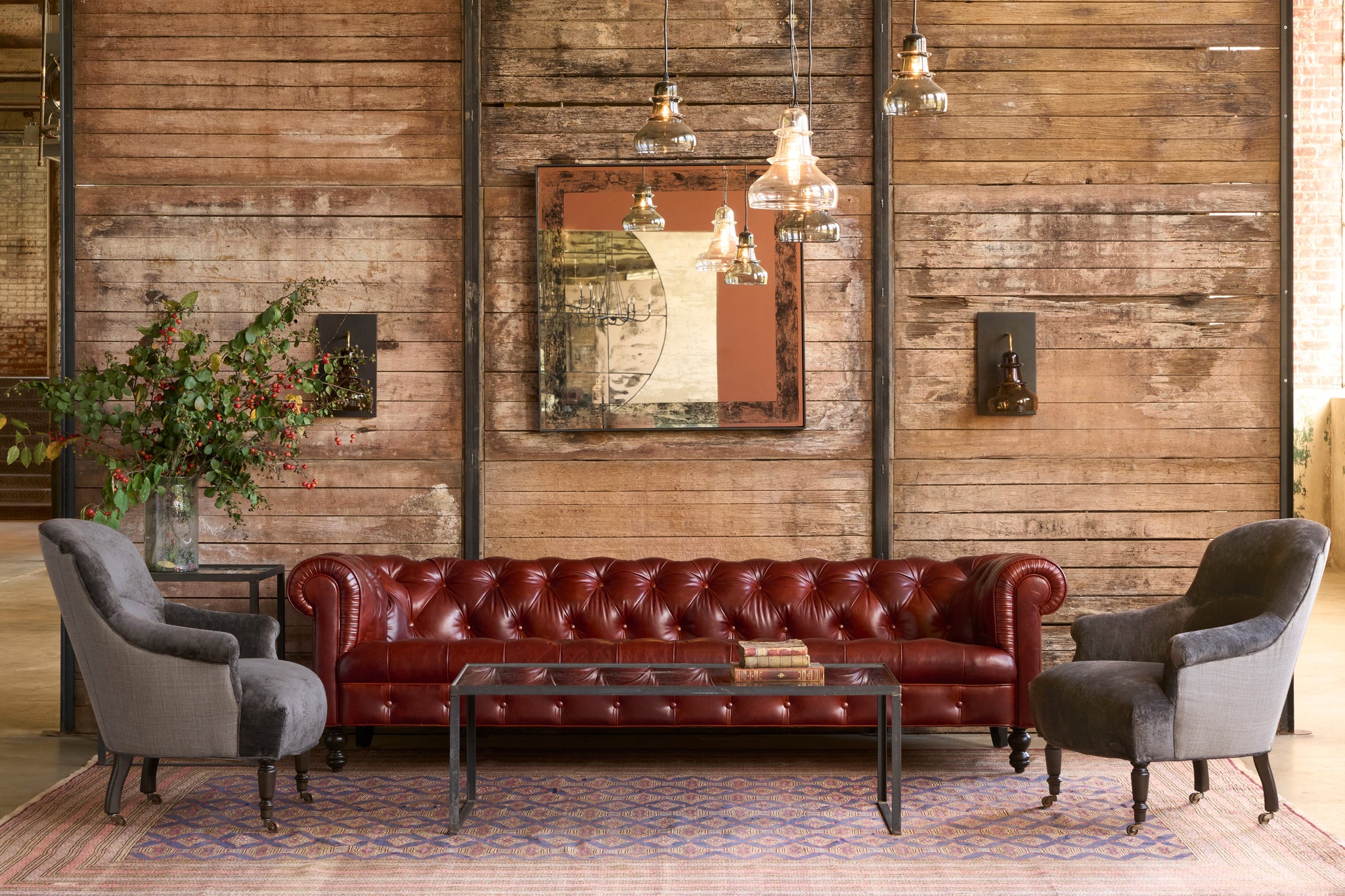  Red leather sofa with two gray armchairs in a room with wooden walls and a painting. Photographed in Solvang Chianti. 