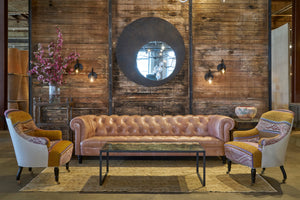  Pink leather tufted sofa in front of a wood wall. Two chair with colorful pattern of each side.Photographed in Solvang Mauve 