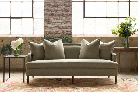 Green sofa in a showroom with white flowers on the left. Photographed in Harris moss.