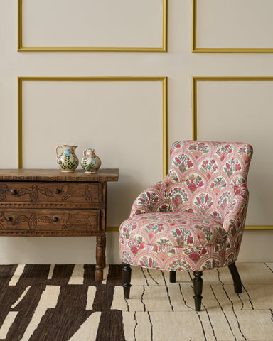 Patterned armchair in a room with a wooden side table and decorative vases. Photographed in Eloise Fresa.
