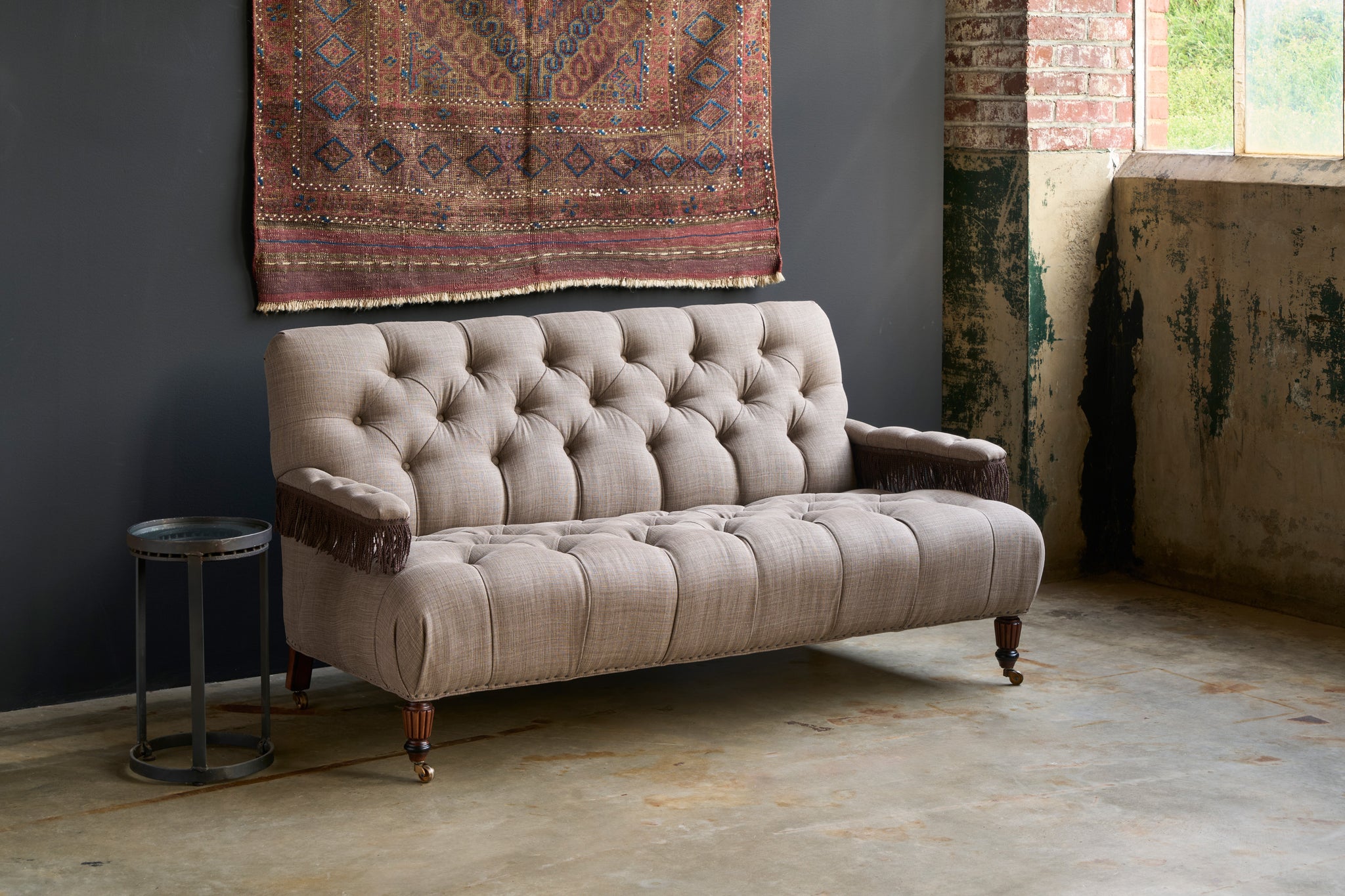  Sofa in front of a black wall and a side table in metal and a carpet hanging. Photographed in JD Rye Acorn. 