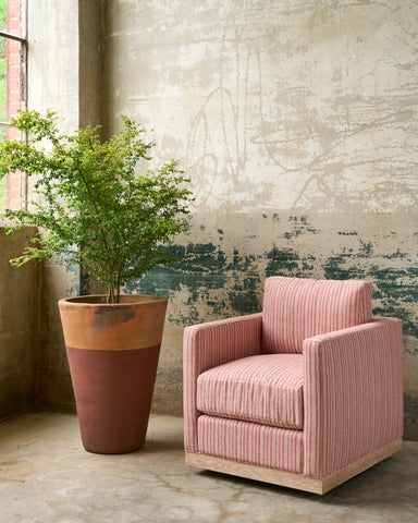 Red and white striped chair with a oak base next to a plant in a pot half painted brown. Photographed in Hickory Persimmon.