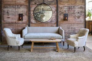  Sofa with 2 chairs in front of a wood wall with a mirror. Photographed in Vintage Hemp. 