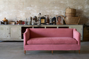  Slipcovered red sofa in front of a cabinet with lots of accessories on top. Photographed in Rye Terra. 