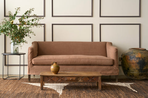 Brown sofa in a room with framed pictures on the wall and a decorative vase on a table. Photographed in JD Rye Spice.
