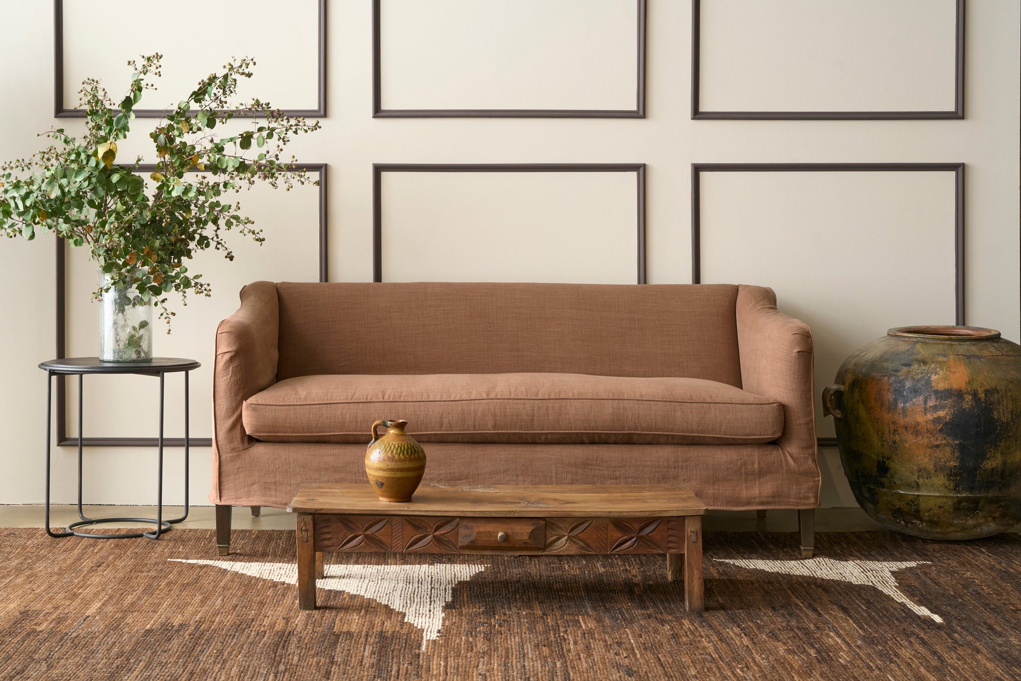  Brown sofa in a living room with a coffee table, decorative vase, and framed pictures on the wall. Photographed in JD Rye Spice. 