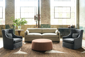  Oatmeal colored sofa with 2 dark grey wing chairs and an orange ottoman on a brown and white rug. Photographed in Rye Black. 