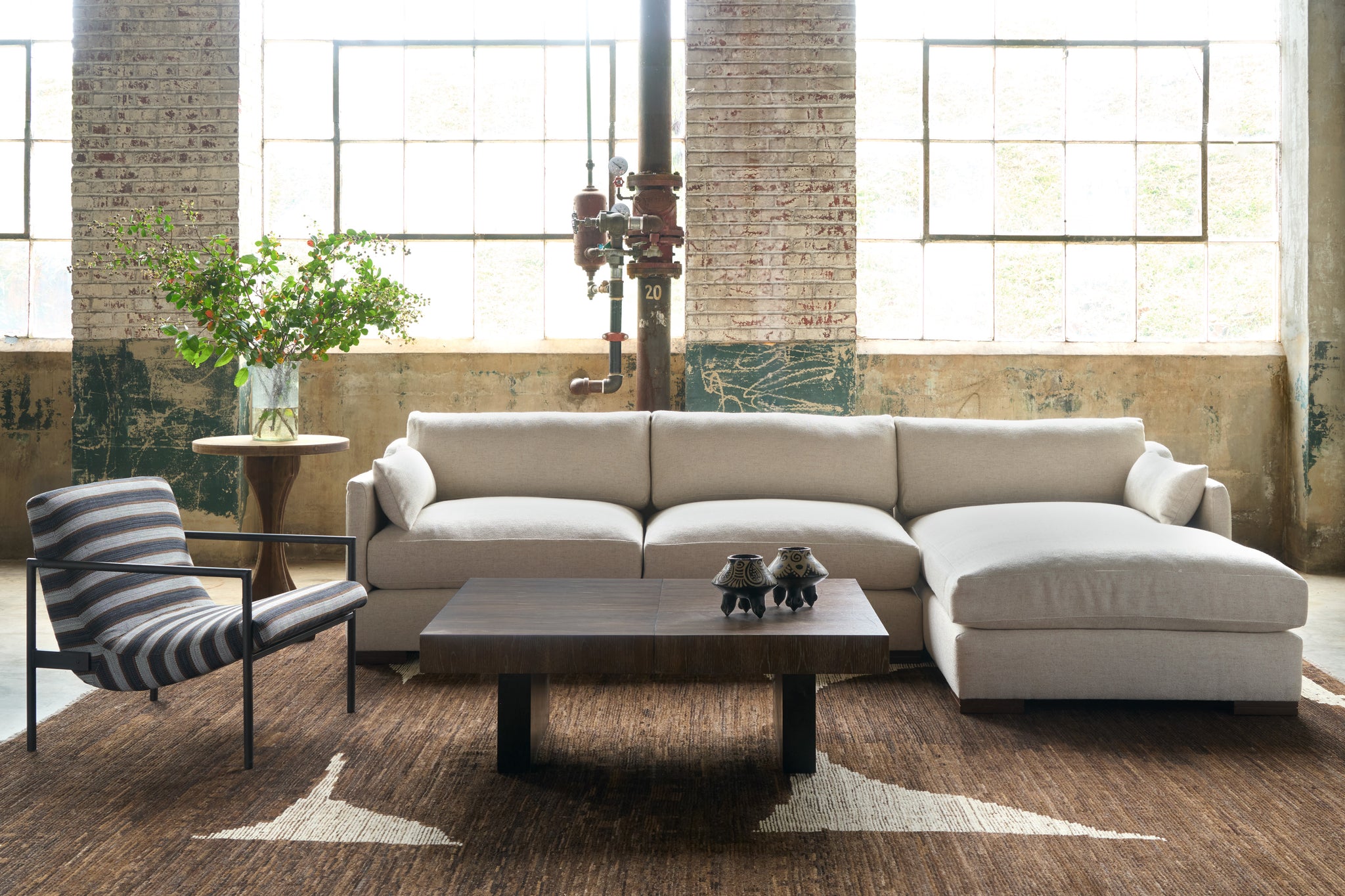  Sectional in a showroom with a striped chair on the left and a wood coffee table in front. Photographed in Bellamy Natural. 