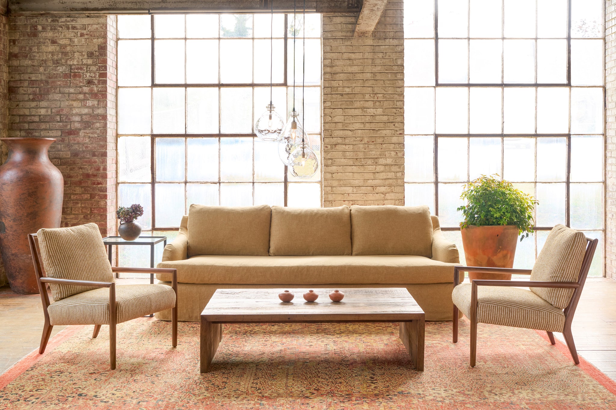  Living room with beige sofa, chairs, and coffee table in front of large windows. Photographed in Harris Wheat. 